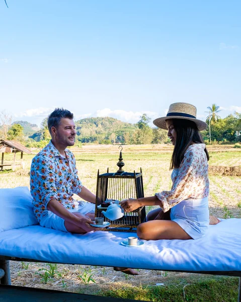 Pareja de hombres y mujeres de vacaciones en Nan Tailandia beber café y té alto con una mirada sobre el campo de Nan Tailandia —  Fotos de Stock