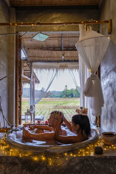 Geceleyin banyoda, banyoda, noel ışıklarıyla, orta yaşlı bir adam ve kadın, Nan Tayland 'da küvette romantik bir gece geçiriyorlar. — Stok fotoğraf
