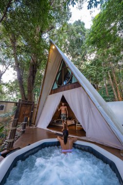 Kuzey Tayland 'da glamping yapan çift ve kadın jaccuzi ile çadırda, Tayland dağlarında bungalovda kadın ve erkek.