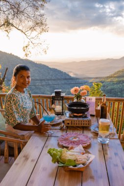 Chiang Mai Tayland 'da akşam yemeği, masa bbq, Asyalı adam ızgarada biftek ve pastırma kullanıyor. Restoranda Kore usulü barbekü büfesi yemek..