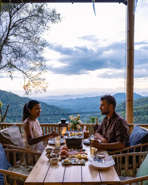 Dinner in the mountains of Chiang Mai Thailand, table bbq, Asian man using kitchen tongs grilling beef and bacon on grill plate. Eating Korean Barbecue buffet in the restaurant. — Stockfoto