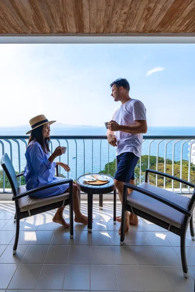 Pareja hombre y mujer bebiendo una taza de café en frente de allí condominio apartamento en Tailandia, mujer asiática y hombre europeo en fron en el balcón del apartamento —  Fotos de Stock