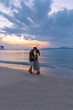 Pattaya Tayland 'da gün batımında, Pattaya Tayland' da gün batımında kumsalda yürüyen çift.