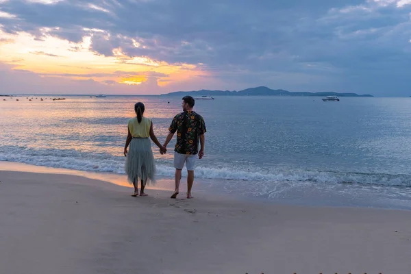 Puesta de sol en la acogedora playa de Pattaya Tailandia, pareja de hombres y mujeres caminando por la playa al atardecer en Pattaya Tailandia — Foto de Stock