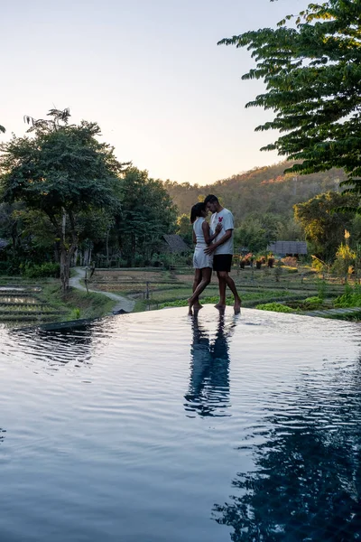 Kuzey Tayland Mae Hong Son 'un dağları ve pirinç tarlalarını gören bir havuzun kenarında gün batımını izleyen çift. — Stok fotoğraf