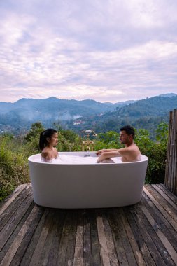 Gün batımında, Chiang Mai Tayland 'ın dağlarında banyo küveti, vahşi doğada, ağaçların arasında jakuzide esneme hareketi.