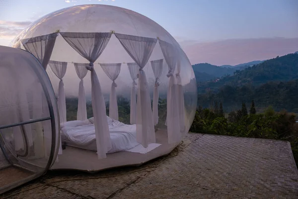 Bubble dome tent glamping in the mountains of Chiang Mai Thailand,Transparent bell tent with comfortable bed and pillow in forest, glamping hotel, luxury travel, glamourous camping