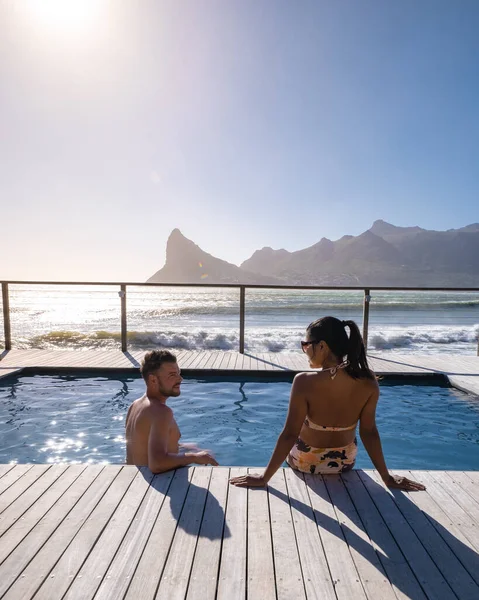 Coppia uomo e donna di fronte alla piscina Infinity affacciata sull'oceano di Città del Capo Sud Africa, uomo e donna in piscina durante il tramonto — Foto Stock