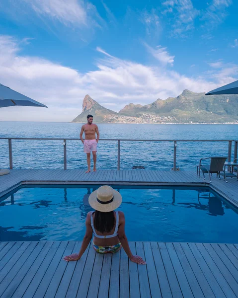 Coppia uomo e donna di fronte alla piscina Infinity affacciata sull'oceano di Città del Capo Sud Africa, uomo e donna in piscina durante il tramonto — Foto Stock