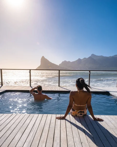 Coppia uomo e donna di fronte alla piscina Infinity affacciata sull'oceano di Città del Capo Sud Africa, uomo e donna in piscina durante il tramonto — Foto Stock