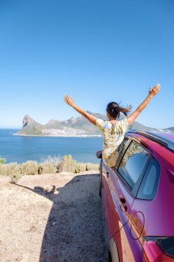 Araba vitrininde elleri havada bir kadın, Chapmans Tepesi yolunda araba Cape Town Güney Afrika 'da okyanusa bakıyor.