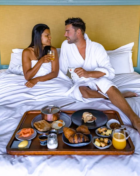 Man en vrouw ontbijten op bed, paar ontbijten met koffiebrood en fruit in de slaapkamer — Stockfoto