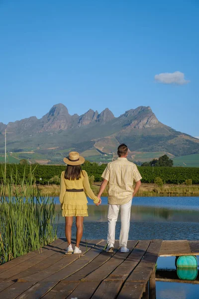 Coppia uomo e donna che si affaccia sul lago, Paesaggio della vigna al tramonto con montagne a Stellenbosch, vicino a Città del Capo, Sud Africa — Foto Stock