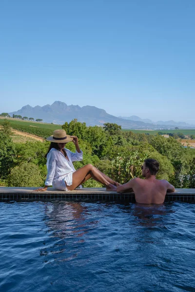 Ζευγάρι άνδρας και γυναίκα στην πισίνα με θέα στους αμπελώνες και τα βουνά του Stellenbosch Νότια Αφρική — Φωτογραφία Αρχείου