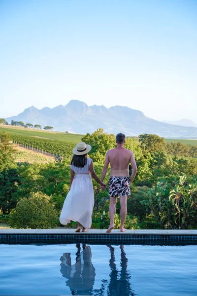 Coppia uomo e donna in piscina con vista sui vigneti e sulle montagne di Stellenbosch Sud Africa — Foto Stock