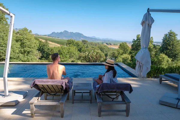 Pareja de hombres y mujeres en la piscina con vistas a los viñedos y montañas de Stellenbosch Sudáfrica —  Fotos de Stock