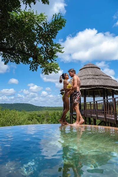 Casal homens e mulheres à beira da piscina em um safário de luxo, África do Sul Kwazulu natal, luxo safari lodge no mato — Fotografia de Stock