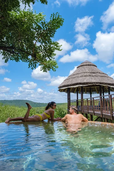 Paar mannen en vrouwen bij het zwembad op een luxe safary, Zuid-Afrika Kwazulu natal, luxe safari lodge in de bush — Stockfoto