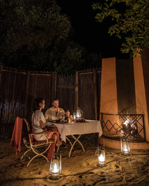 Pár muž a žena, kteří mají večeři v buši v noci, Jižní Afrika Kwazulu natal, luxusní safari Lodge v buši — Stock fotografie