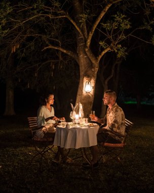 couple men and woman on a romantic dinner on a luxury safary,South Africa, luxury safari lodge in the bush clipart