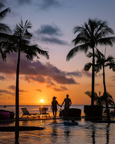 Naplemente trópusi medence pálmafákkal, pár férfi és nő nézi naplementét a medence pálmafákkal nyaralás közben Mauritius — Stock Fotó
