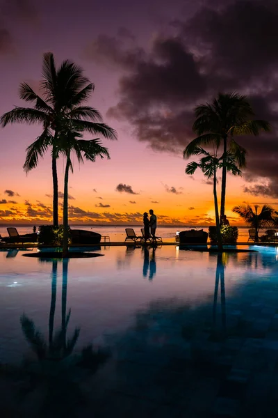 Por do sol piscina tropical com palmeiras, casal homem e mulher assistindo por do sol na piscina com palmeiras durante as férias em Maurício — Fotografia de Stock