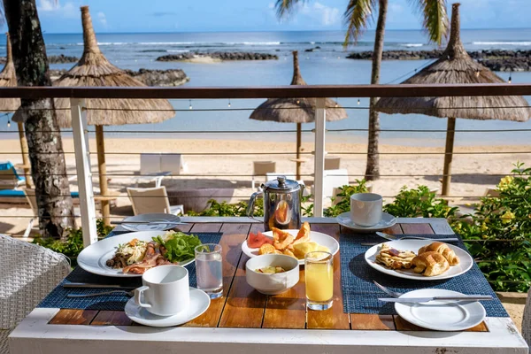 Mauritius 'ta palmiye ağaçları ve havuzu olan bir plajda kahvaltı kahvaltıda, kahvaltıda tropikal bir ortam. - Stok İmaj