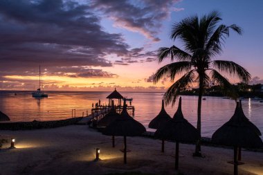 Lüks bir tatil sırasında tropik palmiye ağaçları olan bir yüzme havuzunun yanında gün batımı