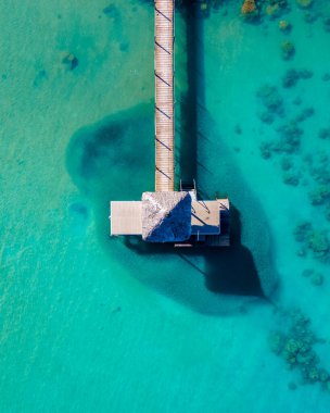 Tropikal bir iskelesi olan mavi bir okyanusun insansız hava görüntüsü