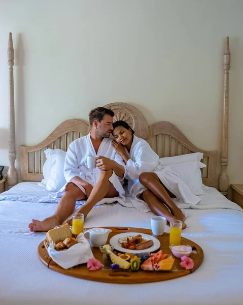 Koppel man en vrouw van middelbare leeftijd ontbijten in bed slaapkamer van een appartement luxe hotel appartement in Mauritius — Stockfoto