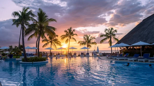 Sunset by a swimming pool with tropical palm trees during a luxury vacation holiday — Foto Stock