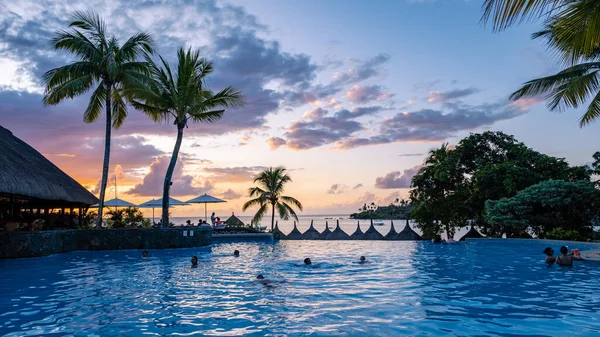 Sunset by a swimming pool with tropical palm trees during a luxury vacation holiday — 스톡 사진
