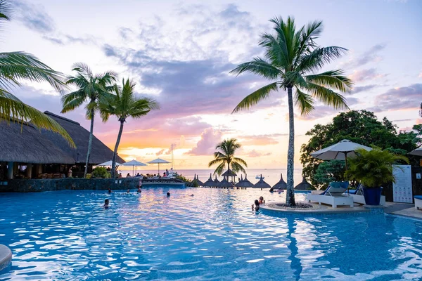 Sunset by a swimming pool with tropical palm trees during a luxury vacation holiday — Fotografia de Stock