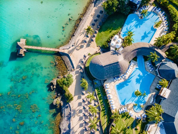 Pięknych tropikalnych przy plaży ośrodek z basenem, leżakami i dłoń drzewa w ciepły słoneczny dzień, przeznaczenia raj na wakacje — Zdjęcie stockowe
