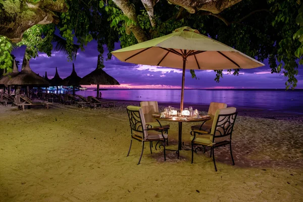 在毛里求斯海滩上的日落，在海滩上有雨伞和椅子的豪华餐厅吃晚饭 — 图库照片
