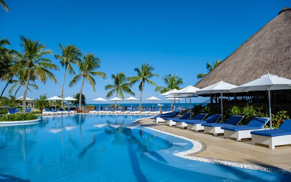 Sıcak güneşli bir gün cennet hedef tatil sırasında güzel tropik sahil otel resort Yüzme Havuzu, güneş-şezlong ve palmiye ağaçları