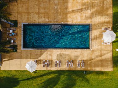 Plaj sandalyeli yüzme havuzu ve lüks bir otelde yemek masası, tropikal bilardo.