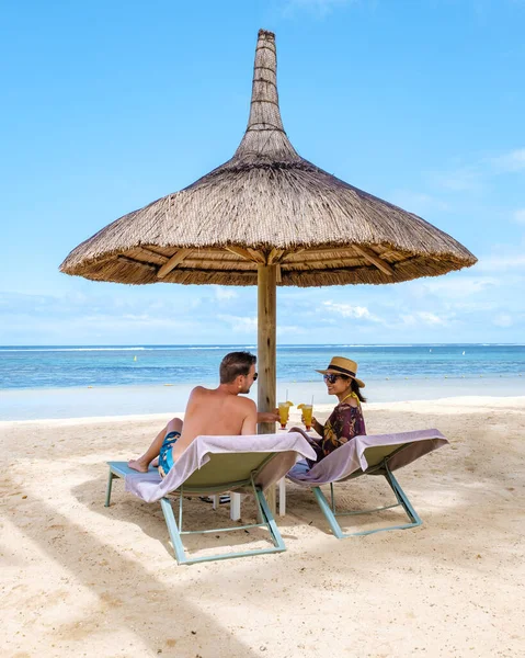 Luna di miele coppia seduta in poltrone di lusso in un resort tropicale sulla spiaggia caraibica e festeggiare con un coctail — Foto Stock