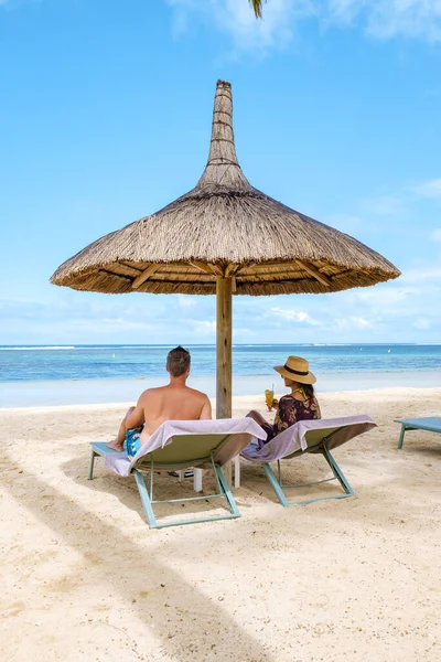 Νεόνυμφο ζευγάρι κάθεται σε πολυτελή ξαπλώστρες σε ένα τροπικό θέρετρο της Καραϊβικής παραλία και γιορτάζει με μια coctail — Φωτογραφία Αρχείου