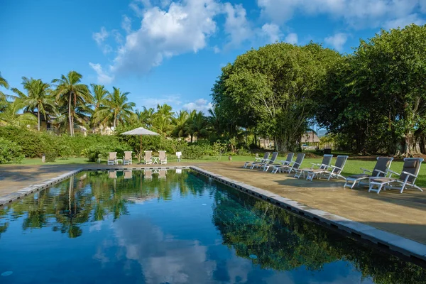 Swimming pool with beach chairs and lunch table at a luxury resort, tropical pool — стоковое фото