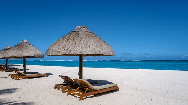 Tropisch strand met palmbomen en wit zand blauwe oceaan en strandbedden met parasol, Zon stoelen en parasol onder een palmboom bij een tropische snavel, Le Morne strand Mauritius — Stockfoto