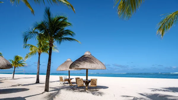 Tropisch strand met palmbomen en wit zand blauwe oceaan en strandbedden met parasol, Zon stoelen en parasol onder een palmboom bij een tropische snavel, Le Morne strand Mauritius — Stockfoto