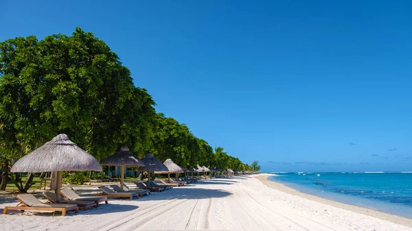 Tropical beach with palm trees and white sand blue ocean and beach beds with umbrella,Sun chairs and parasol under a palm tree at a tropical beac, Le Morne beach Mauritius — Foto de Stock