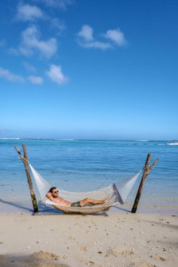 Okyanusta hamağı olan tropik plaj, hamağı olan beyaz kumlu plaj Le Morne plajı Mauritius hamağı olan genç erkekler.