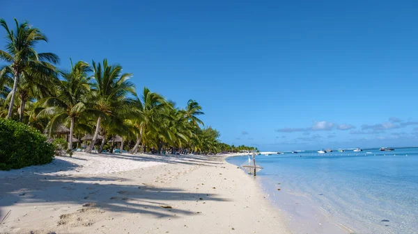 야자나무와 흰 모래로 덮여 있는 열 대의 해변 과푸른 바 다 와 우산 이 있는 해변, 태양 의자와 양산 이 있는 열 대의 비나무, 르모르네 해변 모리셔스에 있는 야자나무 밑의 열대 해변 — 스톡 사진