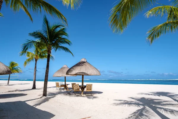 Playa tropical con palmeras y arena blanca azul océano y camas de playa con sombrilla, tumbonas y sombrilla bajo una palmera en una playa tropical, Playa de Le Morne Mauricio — Foto de Stock