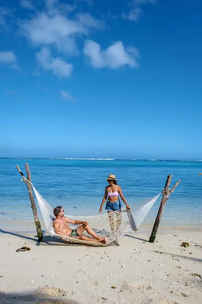 Spiaggia tropicale con amaca nell'oceano, spiaggia di sabbia bianca con amaca Spiaggia di Le Morne Mauritius, coppia di uomini e donne in amaca — Foto Stock