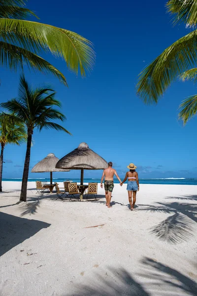 Praia tropical com palmeiras e areia branca azul oceano e camas de praia com guarda-chuva, cadeiras de sol e guarda-sol sob uma palmeira em um beac tropical, Le Morne praia Maurício — Fotografia de Stock