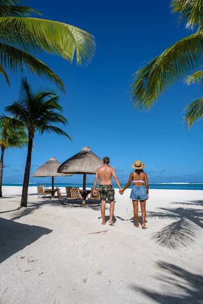 Tropical beach with palm trees and white sand blue ocean and beach beds with umbrella,Sun chairs and parasol under a palm tree at a tropical beac, Le Morne beach Mauritius — Stockfoto