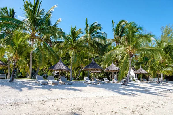 热带海滩，有棕榈树和白沙滩蓝色海洋，海滩床，有雨伞，太阳椅和阳伞，棕榈树下有热带海滩，毛里求斯勒莫尔纳海滩 — 图库照片